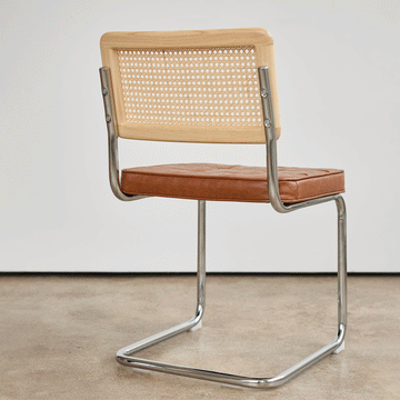 A GIF of dark wash denim on a chair, going on and off with brown loafers underneath. 