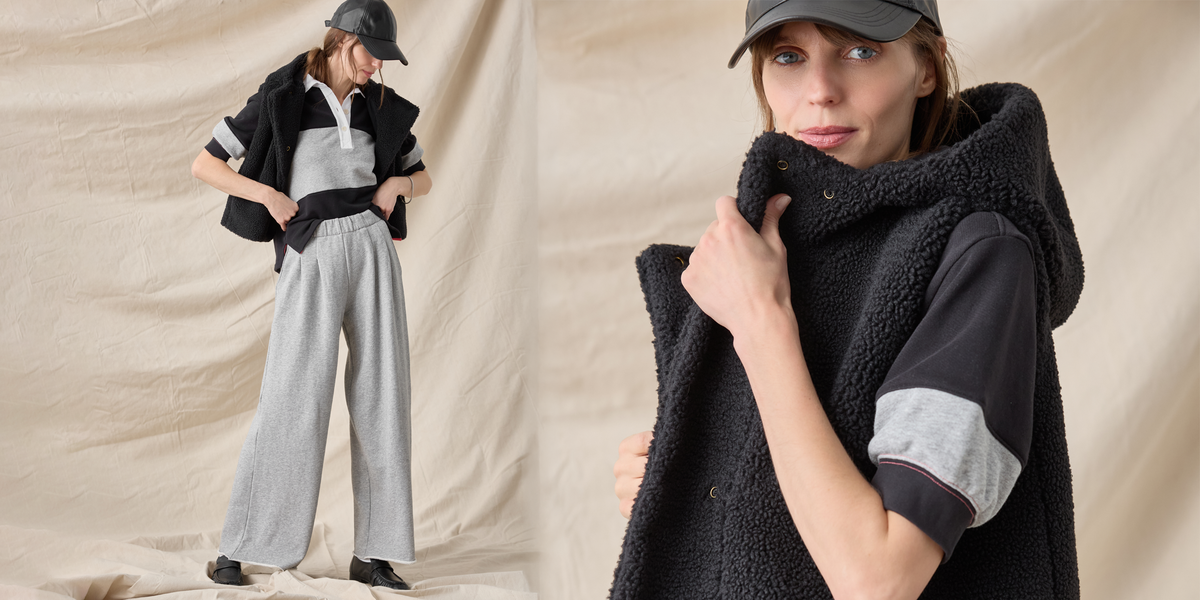 A model wears a black fleece-lined sleeveless vest over a black, white, and gray short-sleeve collared shirt, paired with light gray wide-leg pants and a black cap. The image features a split composition with a full-body view on the left and a close-up of the vest's texture on the right, set against a draped beige fabric backdrop.
